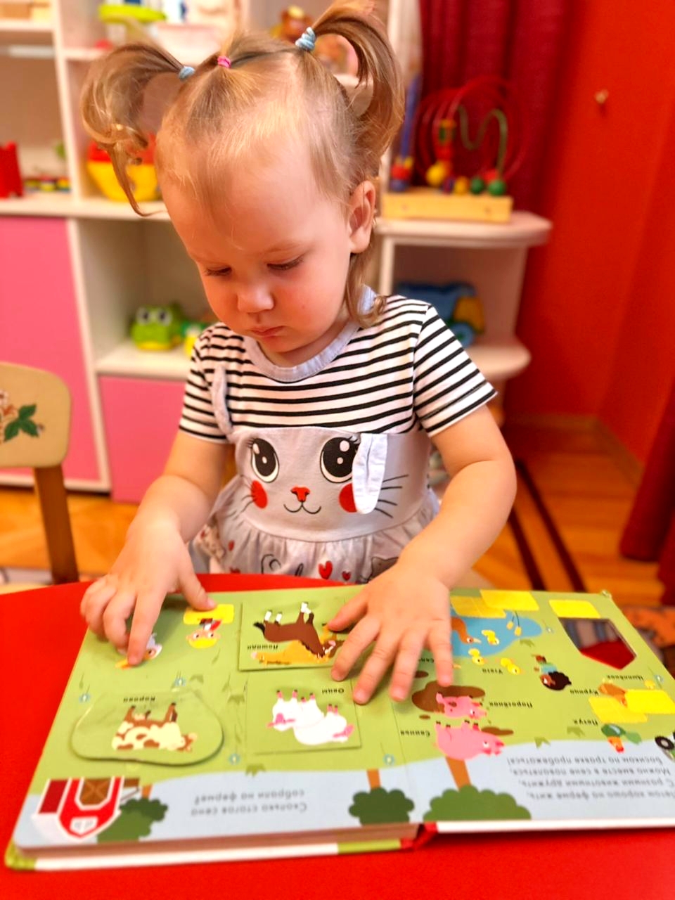 Малышка рассматривает книжку с животными фермы